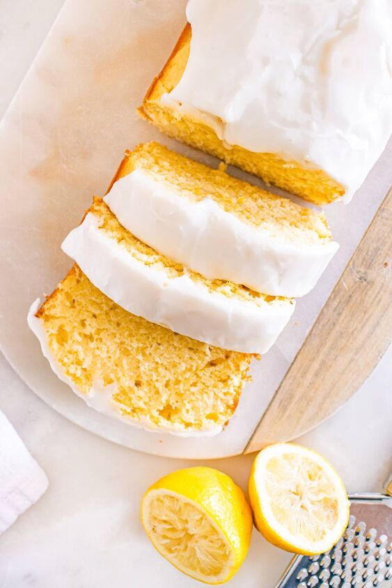 starbucks copycat lemon loaf, Sliced lemon loaf with white icing next to a zested lemon and a grater on a marble surface