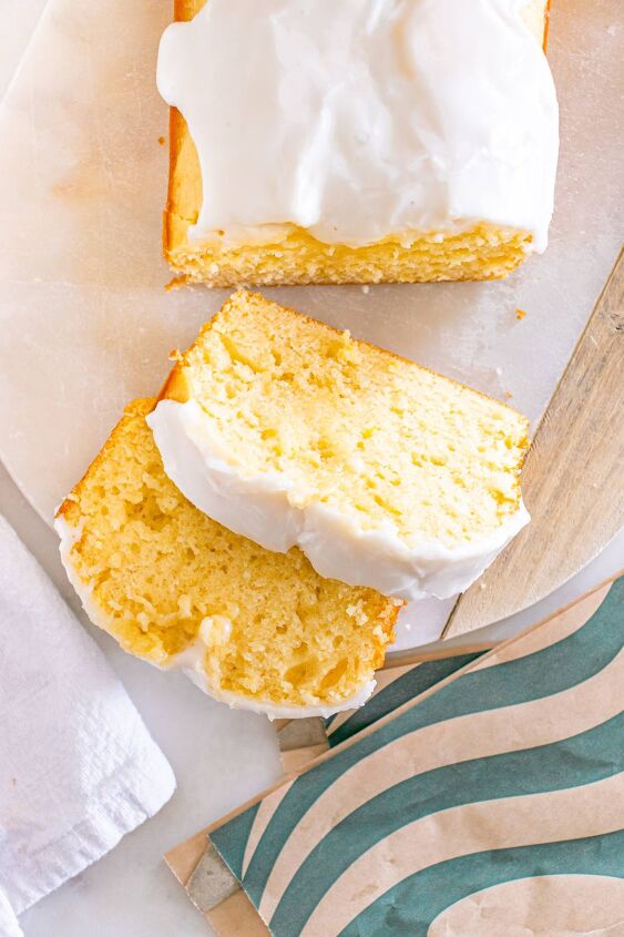 starbucks copycat lemon loaf, Sliced lemon loaf cake with white icing on a marble board next to a green striped napkin