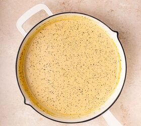 creamy salmon pasta, A white skillet filled with a creamy speckled yellow sauce sits on a light beige countertop