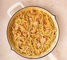 creamy salmon pasta, A white skillet filled with creamy pasta and chunks of cooked salmon sits on a light colored countertop