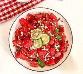 refreshing watermelon strawberry salad recipe, Bowl of fresh watermelon strawberry salad topped with feta cheese lime slices and mint leaves on a white background with red gingham napkin