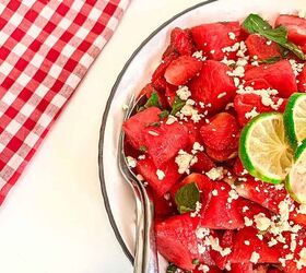 refreshing watermelon strawberry salad recipe, Close up of spoon in a vibrant watermelon strawberry feta salad with fresh mint and lime set against a red checkered cloth and lime slices