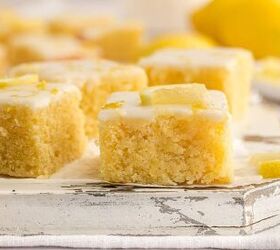 lemon brownies recipe, Lemon brownies with white icing and lemon slices on top arranged on a rustic white wooden surface