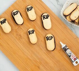 graveyard dirt cake cups easy no bake halloween, Milano cookies decorated with black icing letters RIP to look like gravestones for Halloween dirt cake placed on a wooden cutting board