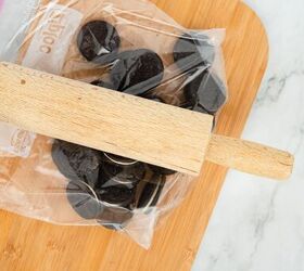 graveyard dirt cake cups easy no bake halloween, Crushing Oreo cookies inside a plastic bag with a rolling pin on a wooden cutting board for dirt cake cups