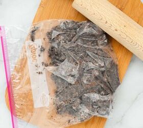graveyard dirt cake cups easy no bake halloween, Crushed Oreo cookies inside a plastic bag with a rolling pin on a wooden cutting board for dirt cake cups