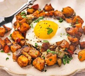 skillet sweet potato breakfast hash easy one pan recipe, Side angle of a plate with sweet potato breakfast hash topped with a sunny side up egg and fresh parsley