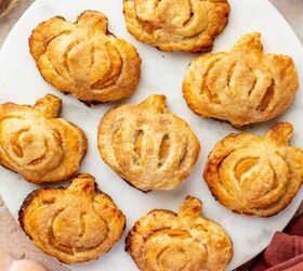 Mini pumpkin shaped hand pies with a golden crust arranged on a marble plate