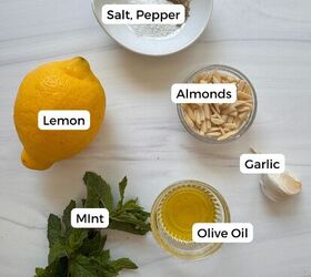 fresh mint pesto vegan gluten free, Ingredients for mint pesto on a white surface a lemon fresh mint leaves a small bowl of slivered almonds garlic salt and pepper and olive oil Each item is labeled for easy preparation