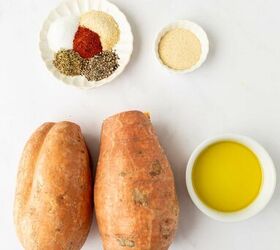 air fryer sweet potato wedges, Two whole sweet potatoes a small bowl of olive oil a small dish with seasonings salt pepper paprika garlic powder dried thyme and a small bowl of breadcrumbs are arranged on a white surface