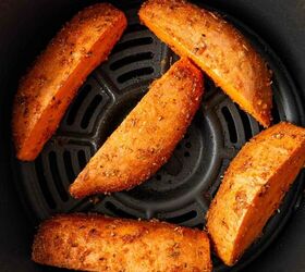 air fryer sweet potato wedges, Five seasoned sweet potato wedges arranged in a single layer inside an air fryer basket ready to be cooked