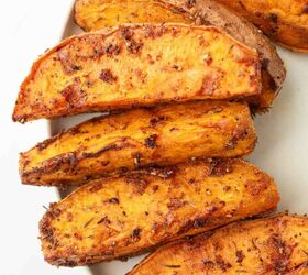 air fryer sweet potato wedges, Close up of several seasoned roasted sweet potato wedges arranged on a white plate The wedges have a crispy golden brown exterior with visible spices and herbs