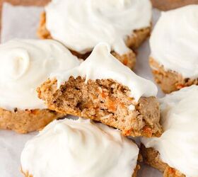 carrot cake cookies, A stack of frosted carrot cake cookies on a wooden surface One cookie is split in half displaying the moist spiced interior with visible pieces of carrot The cookies are topped with smooth cream cheese frosting