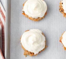 carrot cake cookies, Carrot Cake Cookies with white cream cheese frosting on a parchment lined baking sheet next to a red striped towel