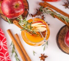 the best fireball apple cider drink for the fall season, Overhead shot of Fireball apple cider cocktails garnished with apple slices rosemary and cinnamon surrounded by apples cinnamon sticks and festive decor