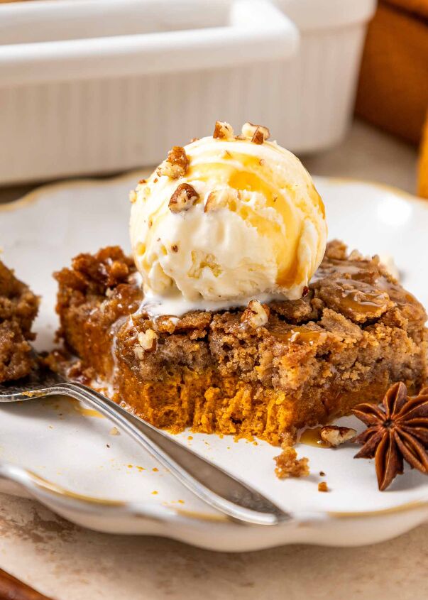 pumpkin dump cake, A slice of pumpkin dump cake topped with a scoop of vanilla ice cream drizzled with caramel sauce and sprinkled with chopped nuts sits on a plate with a fork and a star anise as garnish