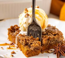 pumpkin dump cake, A fork rests in a slice of spiced pumpkin dump cake topped with a scoop of vanilla ice cream chopped pecans and caramel drizzle on a white plate An anise star garnish sits beside the dessert