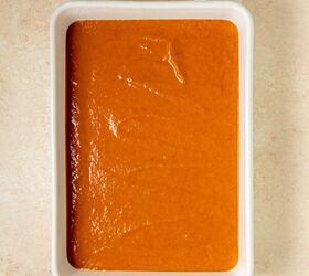 pumpkin dump cake, A white rectangular baking dish filled with a smooth layer of orange brown dump cake batter set on a light beige textured surface