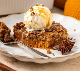 pumpkin dump cake, A slice of pumpkin dump cake topped with a scoop of vanilla ice cream drizzled with caramel sauce and garnished with chopped nuts and a star anise on a decorative white plate A fork holds a bite of the cake