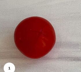 cherry tomato confit with basil and thyme mediterranean style, A single red cherry tomato with a small X shaped cut on top placed on a light colored textured surface perfect for Mediterranean style dishes A white circle with the number 1 is in the bottom left corner