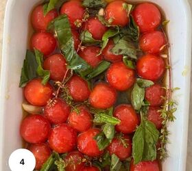 cherry tomato confit with basil and thyme mediterranean style, A white dish filled with round red cherry tomato confit fresh green basil and thyme and herbs all marinated in a golden olive oil for a Mediterranean style touch A white circle with the number 4 is in the bottom left corner