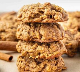 pumpkin oatmeal cookies, A stack of four pumpkin oatmeal cookies sits on a light surface with more cookies and cinnamon sticks in the background The cookies have a soft chunky texture and a golden brown color
