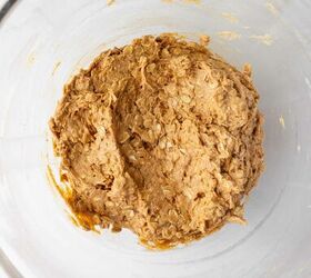 pumpkin oatmeal cookies, A large glass bowl containing a thick light brown oatmeal cookie dough mixture viewed from above on a white surface