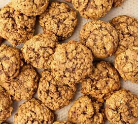 pumpkin oatmeal cookies, A batch of pumpkin oatmeal cookies is scattered on parchment paper with a few cinnamon sticks placed among them The cookies appear soft and have a rustic homemade texture