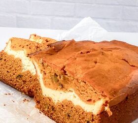 perfectly moist cream cheese pumpkin bread recipe, Whole loaf of cream cheese pumpkin bread on parchment paper with a creamy swirl visible inside after slicing