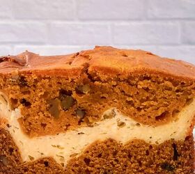 perfectly moist cream cheese pumpkin bread recipe, Side view of a thick slice of cream cheese pumpkin bread on parchment paper showing the distinct cream cheese layer