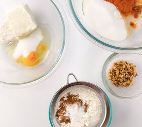 perfectly moist cream cheese pumpkin bread recipe, Ingredients for cream cheese pumpkin bread laid out in glass bowls on a white surface softened cream cheese egg sugar flour pumpkin pur e vanilla baking spices in a sieve and chopped walnuts