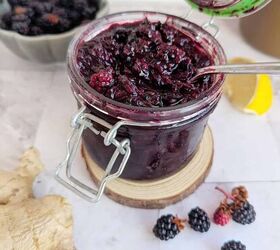 chunky blackberry compote with fresh ginger, An open jar of blackberry ginger jam Blackberries on table infront ginger by the side and a slice of lemon behind
