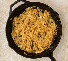french onion pasta, A cast iron skillet filled with golden brown caramelized onions sits on a light beige countertop