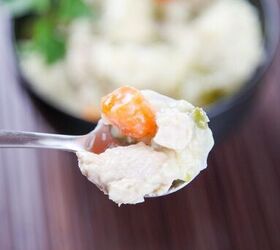 best instant pot chicken and dumplings, a spoon holding chicken and dumplings with carrots and celery with a bowl blurred in the background