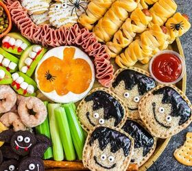 spooky sweet the ultimate halloween charcuterie board, A round platter with Halloween themed snacks including mummy wrapped sausages ghost cookies monster sandwiches veggie sticks resembling monsters bat shaped cookies pretzels candy eyes and dips for a festive party