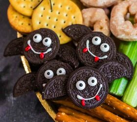 spooky sweet the ultimate halloween charcuterie board, A festive snack platter features bat shaped cookies made from chocolate sandwich cookies with candy eyes and icing smiles surrounded by crackers donuts celery and pretzel sticks A fake spider sits on the crackers