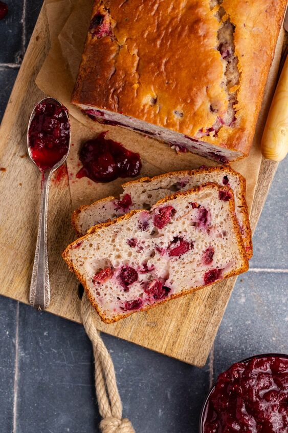 cranberry sauce bread, Cranberry Sauce Bread on a cutting board from above with a spoon of leftover sauce