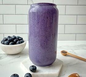 blueberry protein shake, Blueberry protein shake in a clear glass with a straw Blueberries chia seeds and nuts surround the glass