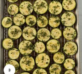mediterranean roasted zucchini slices, Roasted zucchini slices arranged on a wire rack over a baking sheet sprinkled with chopped herbs and seasonings ready to be baked