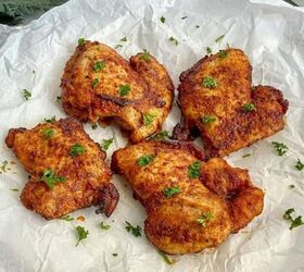 air fryer pork belly crispy bites, Boneless Skinless Chicken Thighs cooked in the air fryer are on parchment paper and sprinkled with fresh green parley