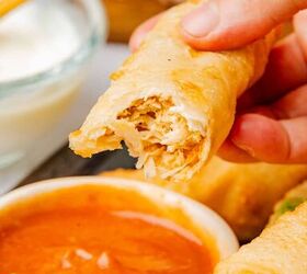 buffalo chicken egg rolls air fryer recipe, A hand holding a buffalo chicken egg roll with a bite taken out to show the mixture on the interior
