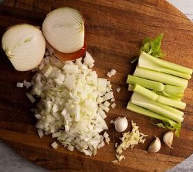 classic american chili, chopped onions celery sticks and chopped garlic on a cutting board