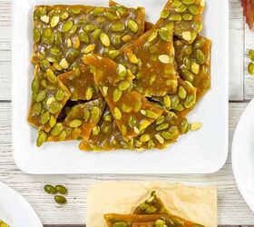 best pumpkin seeds brittle sweet nutty crunchy, Top view of pumpkin seed brittle pieces stacked on a white plate with fall decor in the background