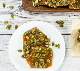 best pumpkin seeds brittle sweet nutty crunchy, Top view of pumpkin seed brittle pieces on a white plate surrounded by scattered pepitas