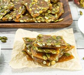 best pumpkin seeds brittle sweet nutty crunchy, Stack of pumpkin seed brittle squares on parchment paper with fall floral decor in the background