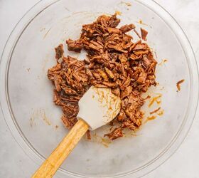 loaded baked potato with brisket, Chopped brisket in a bowl tossed in BBQ sauce with a spatula
