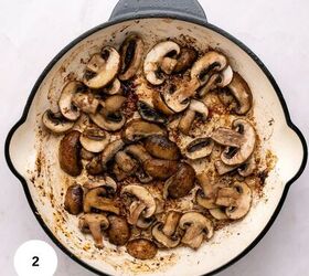 juicy chicken marsala thighs gf one skillet, Sliced mushrooms being saut ed in a white skillet showing browning and caramelization perfect for Chicken Marsala The skillet rests on a light colored surface with a small white circle marked