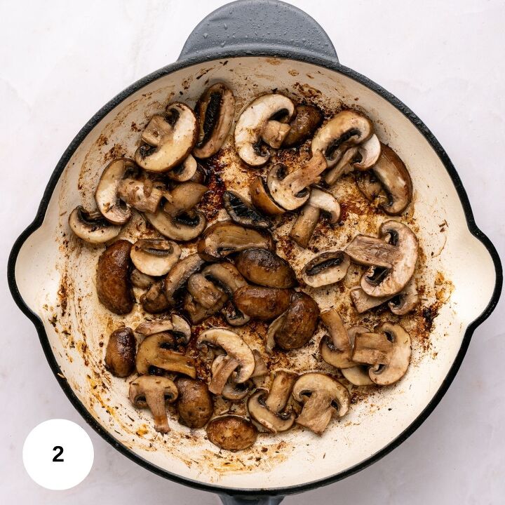 juicy chicken marsala thighs gf one skillet, Sliced mushrooms being saut ed in a white skillet showing browning and caramelization perfect for Chicken Marsala The skillet rests on a light colored surface with a small white circle marked