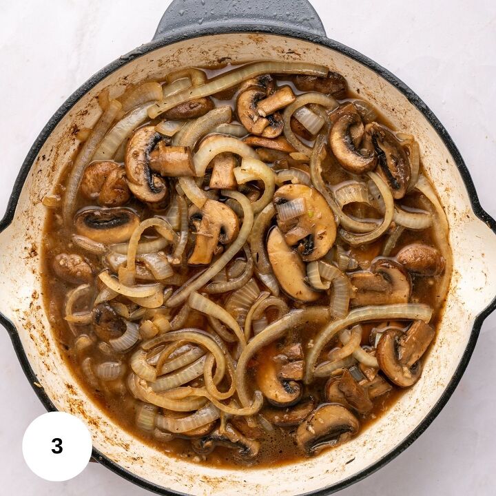 juicy chicken marsala thighs gf one skillet, Sliced mushrooms and onions cooked in a brown sauce fill a white skillet with a black rim creating a classic Chicken Marsala look on a light countertop perfect for a one skillet gluten free meal
