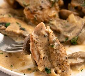 juicy chicken marsala thighs gf one skillet, A close up of a fork holding a piece of chicken marsala covered in creamy mushroom sauce garnished with chopped herbs with more saucy chicken thighs and mushrooms on a white plate all made in one skillet in the background